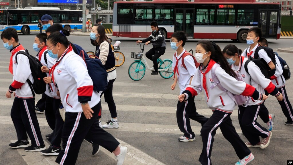 带着口罩的北京小学生穿过一条交通繁忙的十字路口。（美联社照片 2021年4月29日）(photo:VOA)