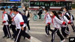 帶著口罩的北京小學生穿過一條交通繁忙的十字路口。（美聯社照片2021年4月29日）