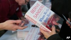 Attendees receive a copy of Sen. Bernie Sanders', I-Vt., new book, 'Where We Go From Here: Two Years in the Resistance', at a George Washington University/Politics and Prose event, Nov. 27, 2018, in Washington.