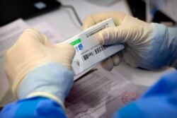 A worker opens a package of coronavirus vaccine made by a Sinopharm subsidiary during a COVID-19 vaccination session for resident foreign journalists at a vaccination center in Beijing, Tuesday, March 23, 2021.