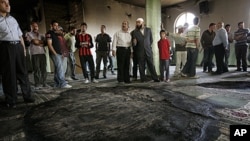 Palestinians inspect the damage following a fire inside a mosque in the West Bank village of al-Mughayyir, near Ramallah, June 7, 2011