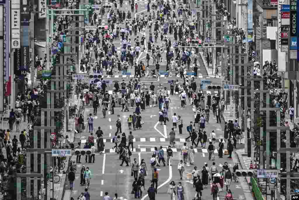 People walk on a street in Tokyo, the same day that some 260 new cases COVID-19 coronavirus infections were recorded in the Japanese capital.