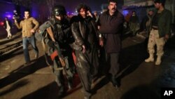 Fuerzas de seguridad afgana asisten a un herido tras la explosión.