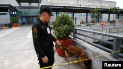 An airport police officer and a sniffer dog patrol Terminal 3 of the Ninoy Aquino International airport in Pasay City, Metro Manila, September 1, 2014.