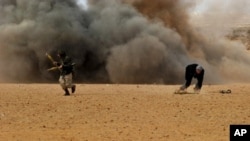 Libyan rebel fighters run for cover as shells explode nearby during a battle with forces loyal to leader Moammer Gadhafi, just few kilometers outside the oil town of Ras Lanuf, March 9, 2011