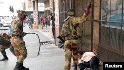 FILE: Soldiers beat a supporter of the opposition Movement for Democratic Change party of Nelson Chamisa outside the party's headquarters as they await the results of the general elections in Harare, Zimbabwe, Aug. 1, 2018.