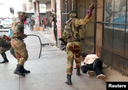 FILE - Soldiers beat a supporter of the opposition Movement for Democratic Change party of Nelson Chamisa outside the party's headquarters as they await the results of the general elections in Harare, Zimbabwe, Aug. 1, 2018.