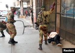 Soldiers beat a supporter of the opposition Movement for Democratic Change party of Nelson Chamisa outside the party's headquarters as they await the results of the general elections in Harare, Zimbabwe, Aug. 1, 2018.