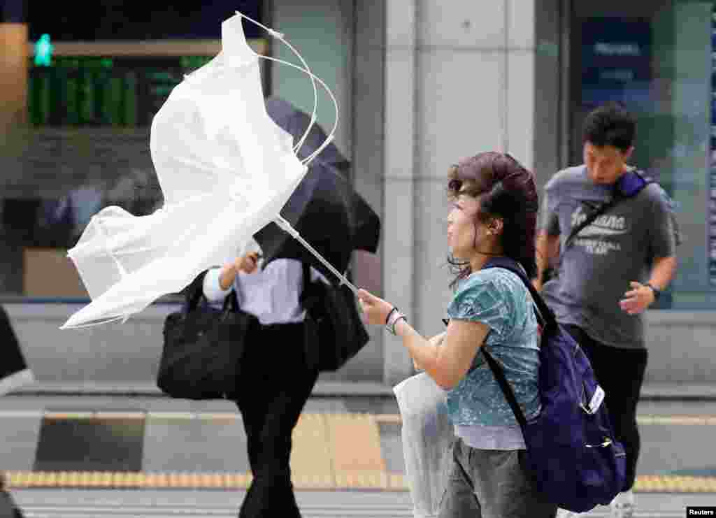 تلاش برای نگهداشتن چتر در مقابل وزش باد و بارش شدید باران در توکیو ژاپن