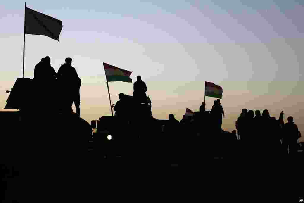 Kurdish Peshmerga fighters stand on top of a military vehicle as they advance towards villages surrounding Mosul, in Khazer, about 30 kilometers (19 miles) east of Mosul, Iraq, Oct. 17, 2016.