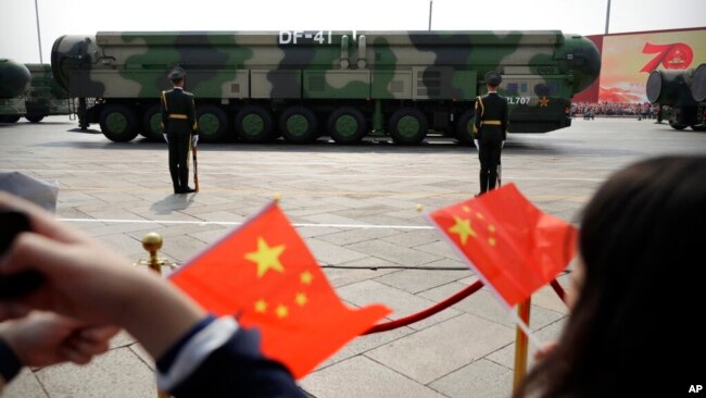 FILE - Spectators wave Chinese flags as military vehicles carrying DF-41 nuclear ballistic missiles roll during a parade to commemorate the 70th anniversary of the founding of Communist China in Beijing on Oct. 1, 2019.