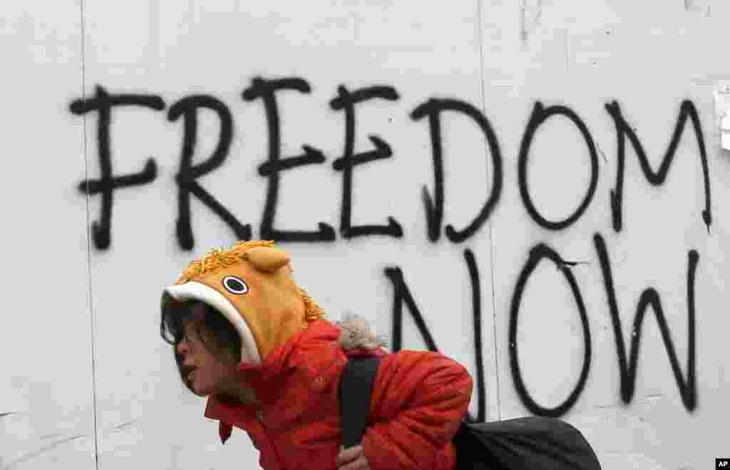 A girl walks by a grafitti at the train station near the makeshift refugee camp at the northern Greek border point of Idomeni.