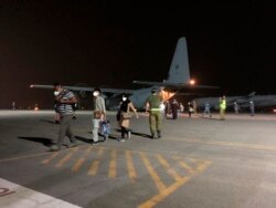 Dalam foto yang disediakan oleh Angkatan Pertahanan Australia ini, para pengungsi dari Afghanistan turun dari pesawat Hercules C-130J Angkatan Udara Australia setelah tiba di pangkalan utama Australia di kawasan Timur Tengah, Rabu, 18 Agustus 2021, (AP)