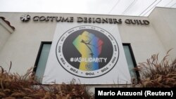 Sebuah spanduk yang menunjukkan solidaritas terhadap Aliansi Internasional Karyawan Panggung Teater (IATSE) terpasang di luar kantor serikat desainer kostum di Burbank, California, pada 7 Oktober 2021. (Foto: Reuters/Mario Anzuoni)