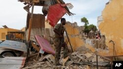 A Somali soldier stands near a destroyed building outside the police traffic station in Mogadishu, Somalia, May, 9, 2016.