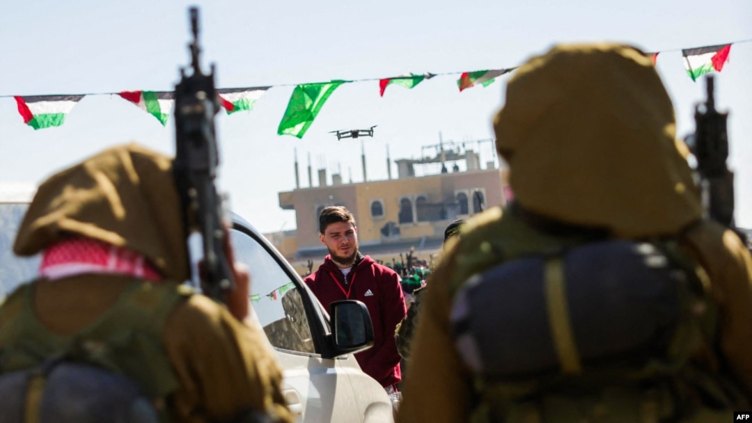 Hamas mengawal sandera Israel-Rusia Sasha Troufanov sebelum menyerahkannya kepada tim Palang Merah di Khan Yunis, Jalur Gaza selatan, pada 15 Februari 2025, sebagai bagian dari pertukaran sandera-tahanan keenam. (Foto: AFP)