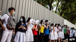 FILE - School students hold signs during a pro-democracy protests near their school in Hong Kong on June 12, 2020.