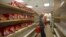 FILE - A man takes a package of cookies surrounded by empty shelves of a supermarket in Caracas, Venezuela, March 23, 2018. 