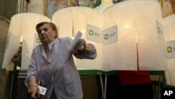 A woman leaves a voting booth at a polling station in Tbilisi, Georgia, October 1, 2012. 