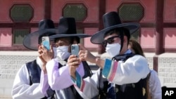 Un grupo de hombres, con mascarilla para protegerse del coronavirus, toman fotografías durante una visita al Palacio de Gyeongbok para celebrar el Chuseok, la versión coreana del Día de Acción de Gracias, en Seúl, Corea del Sur, el 22 de septiembre de 2021. 