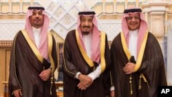 Dalam foto yang dirilis oleh Kantor Berita Arab Saudi ini, Menteri Perekonomian dan Perencanaan baru, Mohammad al-Tuwaijri (kanan) dan kepala Garda Nasional yang baru, Pangeran Khalid bin Ayyaf al-Muqrin (kiri) berpose bersama Raja Salman dalam upacara pengambilan sumpah jabatan di Riyadh, Arab Saudi, 6 November 2017. (Foto: dok/Saudi Press Agency, via AP).