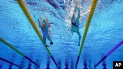 Swimmers warmup before the start of an evening aquatics session at the 2020 Summer Olympics, July 30, 2021, in Tokyo, Japan.