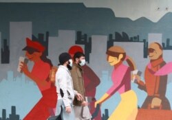 Men wearing face masks walk past a mural in Cape Town, South Africa, May 27, 2020.