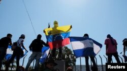 FILE - Anti-government protesters hold flags and shout slogans to riot police during a demonstration against Nicaraguan President Daniel Ortega's government in Managua, Nicaragua, March 30, 2019. 