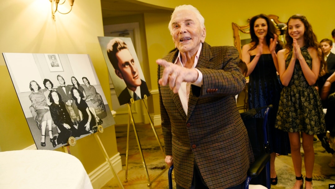 Actor Kirk Douglas arrives at his 100th birthday party as his daughter-in-law Catherine Zeta-Jones (second from right) and her daughter Carys applaud at the Beverly Hills Hotel, Dec. 9. 2016, in Beverly Hills, Calif.