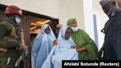 An official embraces a girl who was kidnapped from a boarding school in the northwest Nigerian state of Zamfara, as she heads for a medical check-up after her release in Zamfara, Nigeria March 2, 2021. (REUTERS/Afolabi Sotunde)