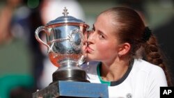 Petenis asal Latvia, Jelena Ostapenko, mencium piala setelah meraih juara di final turnamen tenis French Open dengan mengalahkan petenis Simona Halep asal Romania dalam tiga set dengan angka 4-6, 6-4, 6-3 di stadion Roland Garros, di Paris, Perancis, hari Sabtu, 10 Juni 2017 (foto: AP Photo/Christophe Ena)