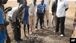 Civilians at the site of a bomb crater in Thaon village in Bentiu town, South Sudan, April 12, 2012. 