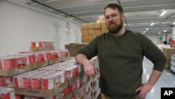 Anthony Reinert, director of programs for the Food Bank of Alaska, poses stands near pallets of canned food at the warehouse in Anchorage, Alaska, on April 4, 2023.