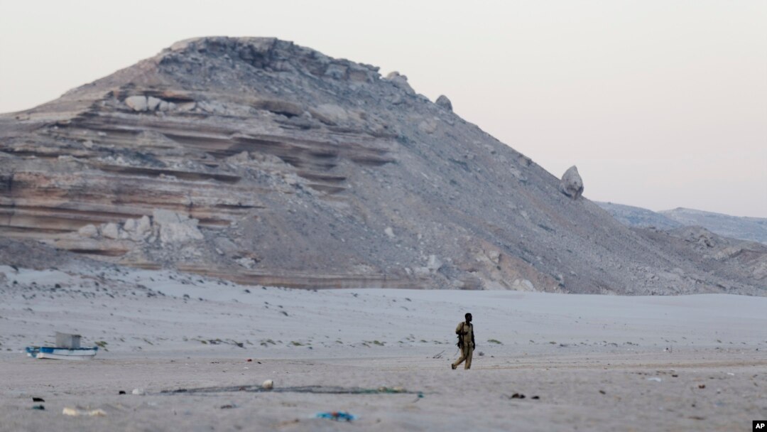 FILE - In this photo taken March 6, 2017, a Somali government soldier walks on the beach in Eyl, in Somalia's semiautonomous northeastern state of Puntland. Somali pirates have seized a small boat, kidnapped its Indian crew members, and are taking the ves