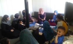 The head of the Women’s Social Rally, Radwa Hassoun, in pink scarf, sits with a group of female refugees in Arsal town in northeastern Lebanon. Arsal is a destination for many Syrians fleeing the war in their country. (Nisan Ahmado/VOA)