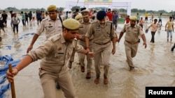 Police officers walk at the site where believers had gathered for a Hindu religious congregation, following which a stampede occurred, in Hathras district of the northern state of Uttar Pradesh, India, July 3, 2024. 
