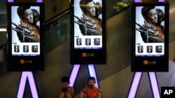 Children use smartphones near monitors displaying a Chinese action movie "Wolf Warrior 2" at a cinema in Beijing, Aug. 10, 2017.