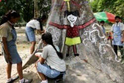 FILE - Indian schoolgirls paint a tree trunk at a park to mark Earth Day in Kolkata, April 22, 2017.
