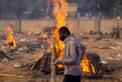 A man walks past burning funeral pyres of people, who died due to the coronavirus disease (COVID-19), at a crematorium ground in New Delhi, India, April 22, 2021.