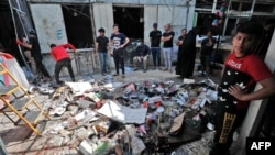 Iraqis inspect the site of the explosion a day earlier in a popular market in the Shiite-majority Sadr City neighborhood, east of the capital Baghdad on July 20, 2021. 