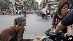 FILE - An older Vietnamese woman begs for money on a busy Hanoi street.