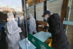 FILE - A man buys a face mask at a pharmacy store following an outbreak of the new coronavirus and the city’s lockdown, in Wuhan, Hubei province, China January 29, 2020. (China Daily via REUTERS)