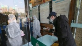 FILE - A man buys a face mask at a pharmacy store following an outbreak of the new coronavirus and the city’s lockdown, in Wuhan, Hubei province, China January 29, 2020. (China Daily via REUTERS)