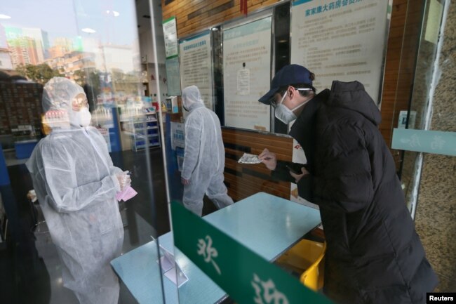 FILE - A man buys a face mask at a pharmacy store following an outbreak of the new coronavirus and the city’s lockdown, in Wuhan, Hubei province, China January 29, 2020. (China Daily via REUTERS)