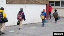 Les points verts sur le sol aident les élèves à garder leurs distances dans cette école canadienne pendant la pandémie de COVID-19, à Saint-Jean-sur-Richelieu au Québec, le 11 mai 2020. (REUTERS/ Christinne Muschi)