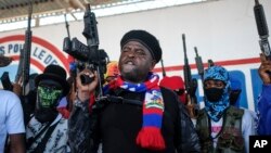 FILE - Leader of the "G9 and Family" gang, Jimmy Cherizier, better known as Barbecue, shouts slogans with his gang members after giving a speech, as he leads a march against kidnappings, through the La Saline neighborhood in Port-au-Prince, on October 22, 2021.