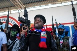 FILE - FILE - Leader of the "G9 and Family" gang, Jimmy Cherizier, better known as Barbecue, shouts slogans with his gang members after giving a speech, as he leads a march against kidnappings, through the La Saline neighborhood in Port-au-Prince, Haiti, Oct. 22, 2021.