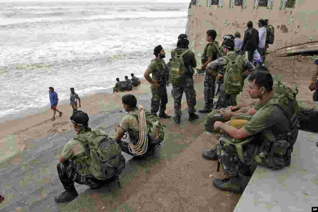 Para anggota Angkatan Udara India menunggu cuaca membaik di sebuah pantai menyusul datangnya Topan Phailin di Gopalpur, negara bagian Orissa di timur India (13/10). (AP/Bikas Das)