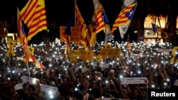 FILE - People light up their mobile phones during a protest called by Catalan pro-independence movements ANC and Omnium Cultural to mark one year of the imprisonment of their leaders Jordi Sanchez and Jordi Cuixart, at Catalunya Square in Barcelona, Spain,