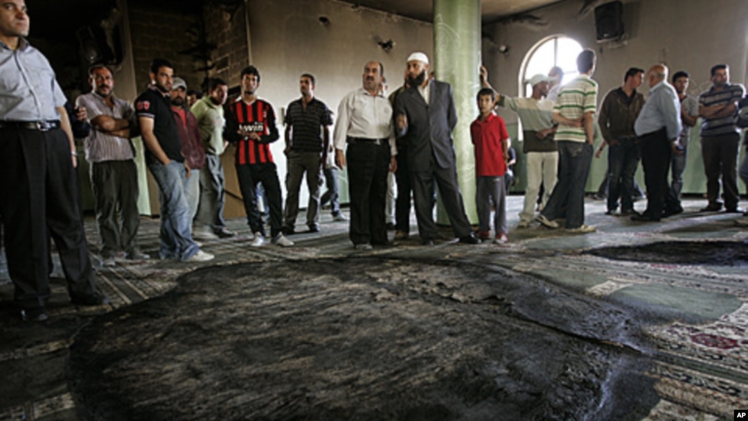 Palestinians inspect the damage following a fire inside a mosque in the West Bank village of al-Mughayyir, near Ramallah, June 7, 2011